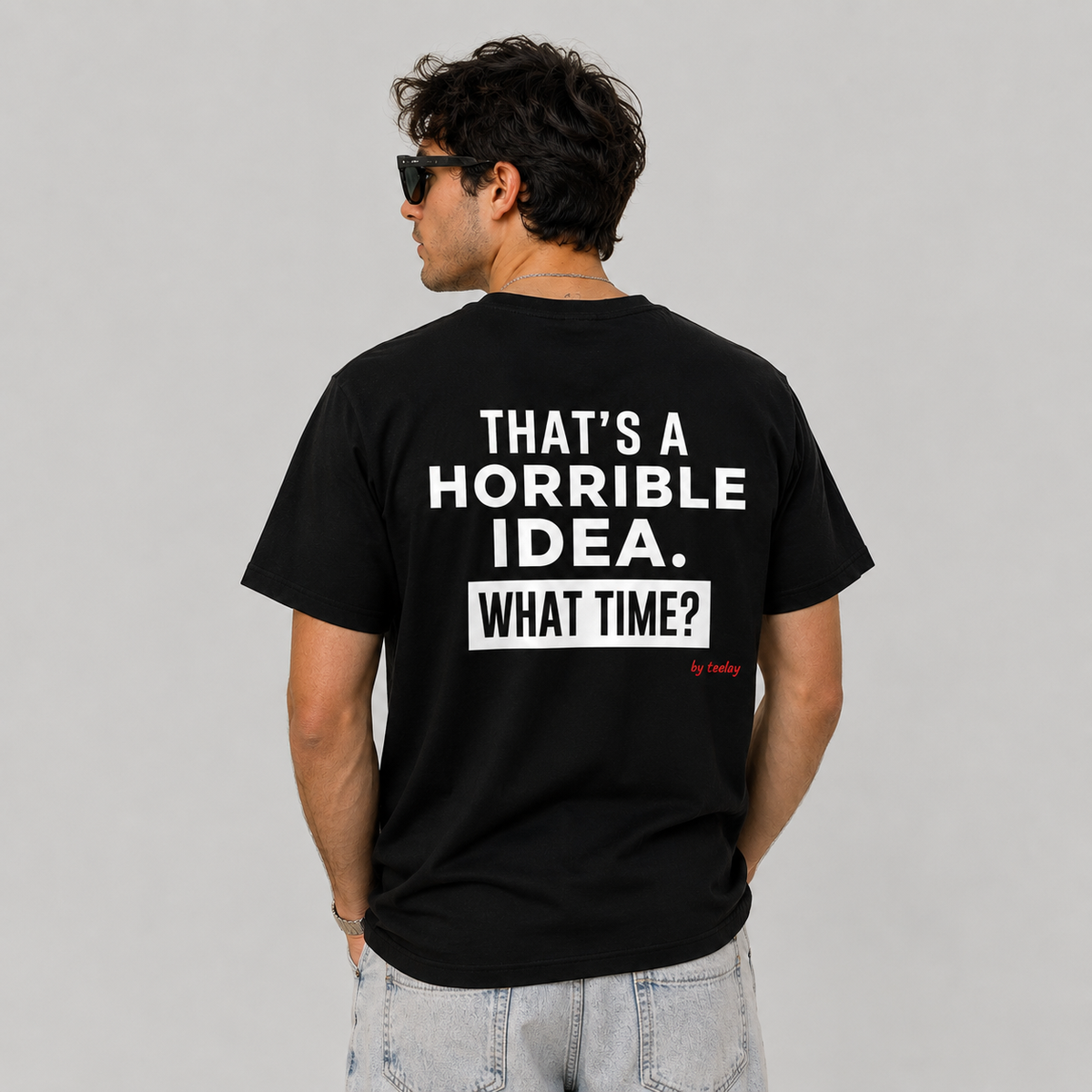 Man in sunglasses wearing a black graphic tee with That's A Horrible Idea What Time on the back