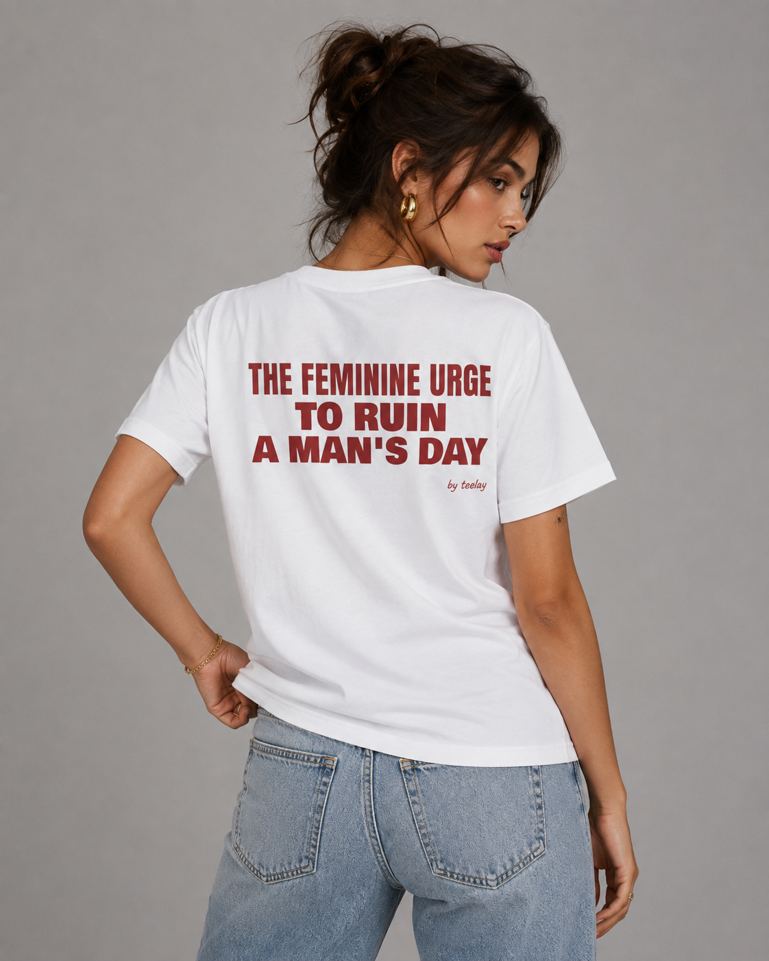 Woman from behind wearing a white t shirt with The Feminine Urge To Ruin A Man's Day printed on the back