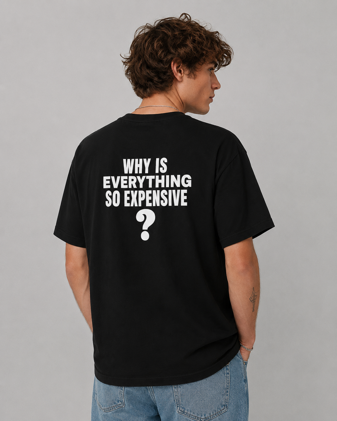 Man from behind wearing a black t shirt with Why Is Everything So Expensive printed on the back