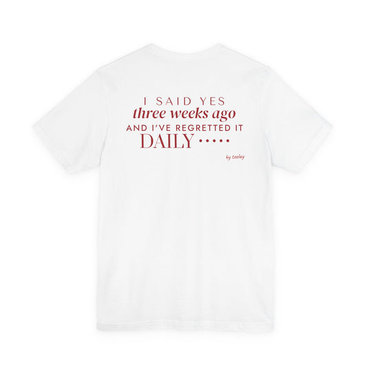 Back of a white t shirt with I Said Yes Three Weeks Ago And I've Regretted It Daily printed in red
