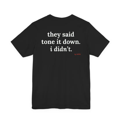 Woman from behind wearing a black oversized t shirt with "They Said Tone It Down. I Didn't." printed on the back