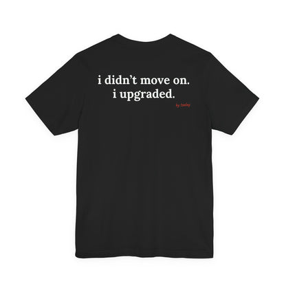 Woman from behind wearing a black oversized t shirt with "I Didn't Move On. I Upgraded." printed on the back