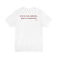 Woman from behind wearing a white oversized t shirt with "You're Not Unlucky. You're Consistent." printed on the back