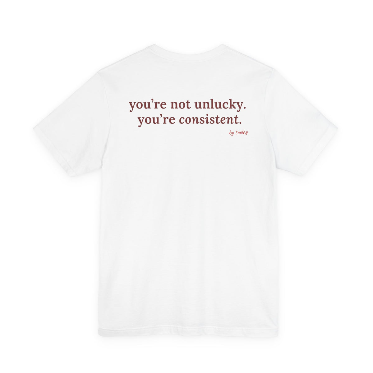 Woman from behind wearing a white oversized t shirt with "You're Not Unlucky. You're Consistent." printed on the back
