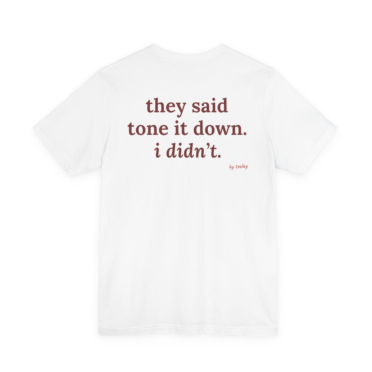 Woman from behind wearing a white oversized t shirt with "They Said Tone It Down. I Didn't." printed on the back
