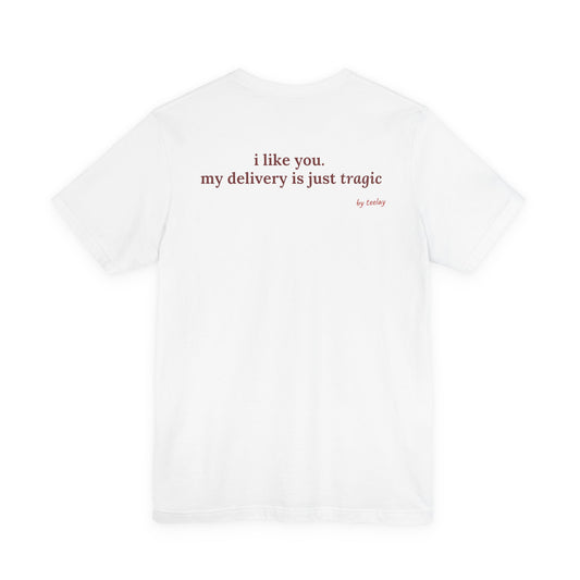Woman from behind wearing a white oversized t shirt with "I Like You. My Delivery Is Just Tragic" printed on the back