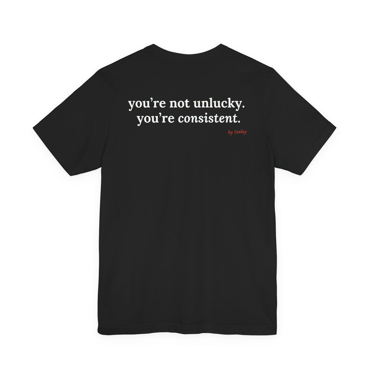 Woman from behind wearing a black oversized t shirt with "You're Not Unlucky. You're Consistent." printed on the back