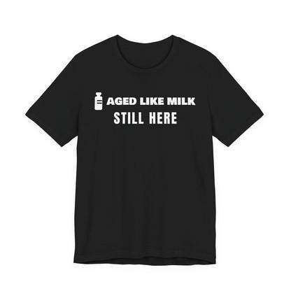 Front of a black t shirt with Aged Like Milk. Still Here. printed in white