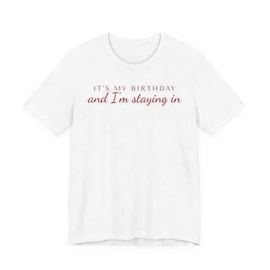 Front of a white t shirt with It's My Birthday And I'm Staying In printed in red
