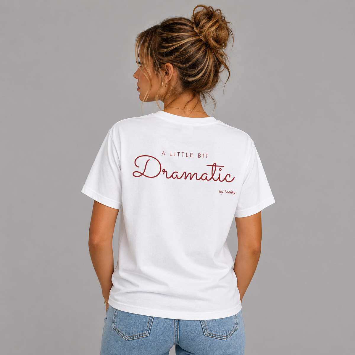 Woman from behind wearing a white t shirt with A Little Bit Dramatic printed on the back