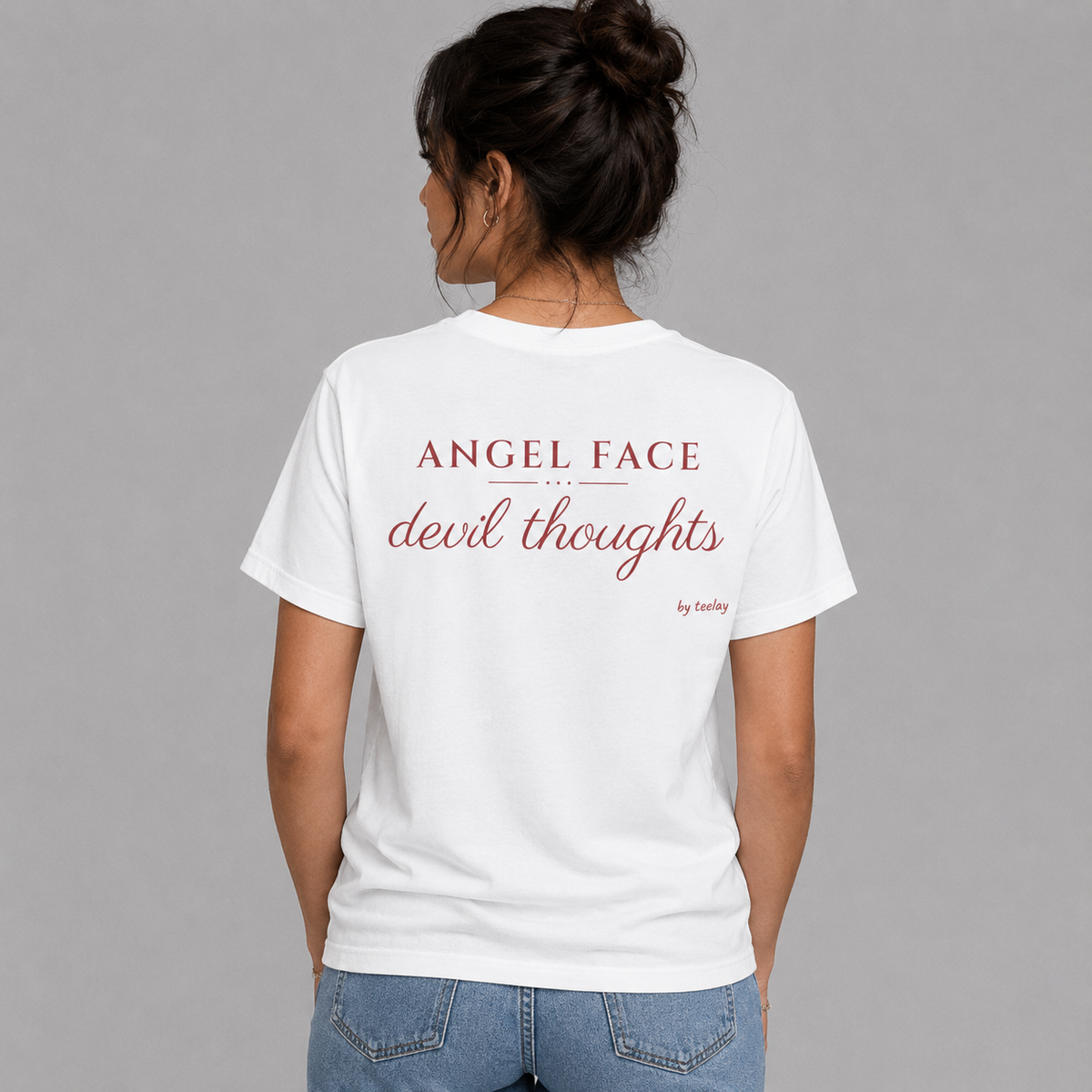 Woman from behind wearing a white t shirt with Angel Face Devil Thoughts printed on the back