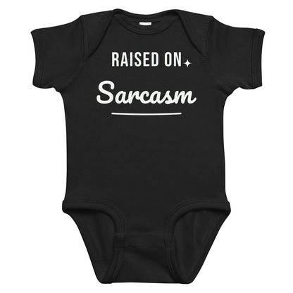 Black baby bodysuit with Raised On Sarcasm printed in white on the front