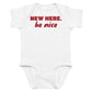 Back view of the black baby bodysuit with New Here Be Nice printed on the front