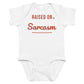 White baby bodysuit with Raised On Sarcasm printed in red on the front