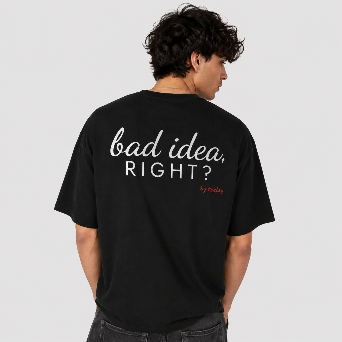 Man from behind wearing a black oversized t shirt with Bad Idea Right printed on the back