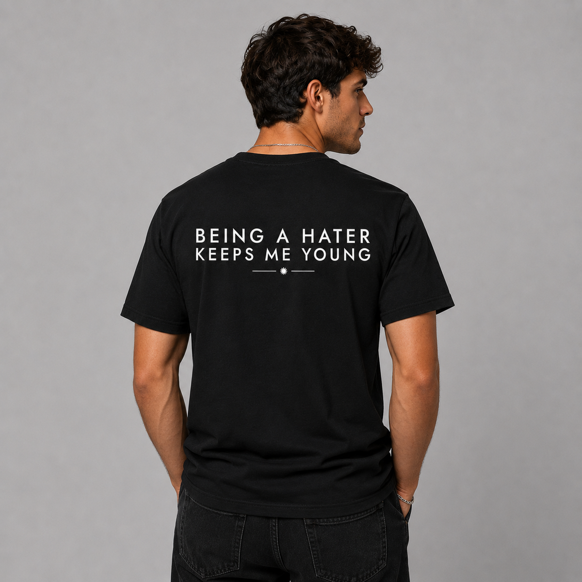 Man from behind wearing a black t shirt with Being A Hater Keeps Me Young printed on the back