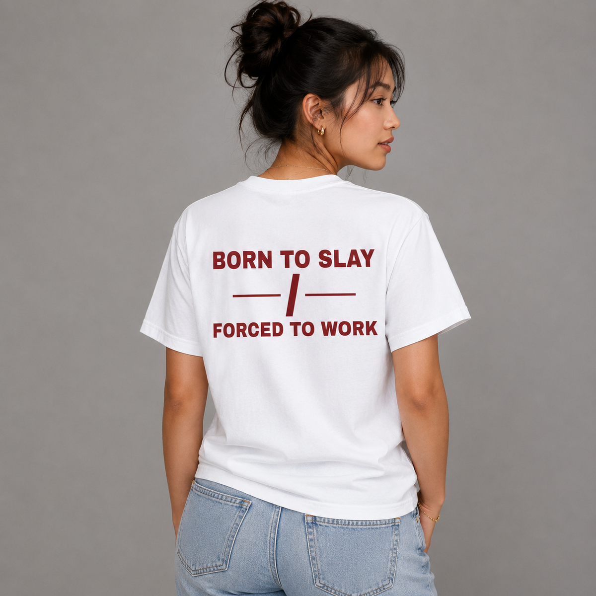 Woman from behind wearing a white t shirt with Born To Slay Forced To Work printed on the back