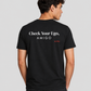 Man from behind wearing a black t shirt with Check Your Ego Amigo printed on the back