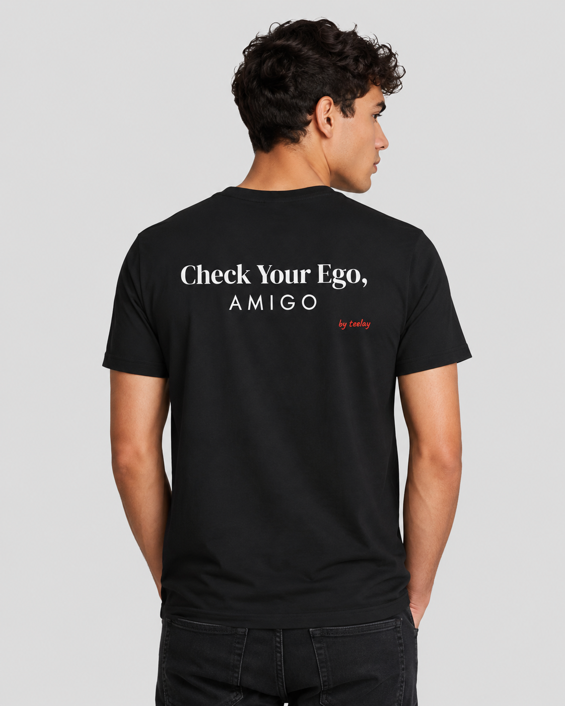 Man from behind wearing a black t shirt with Check Your Ego Amigo printed on the back
