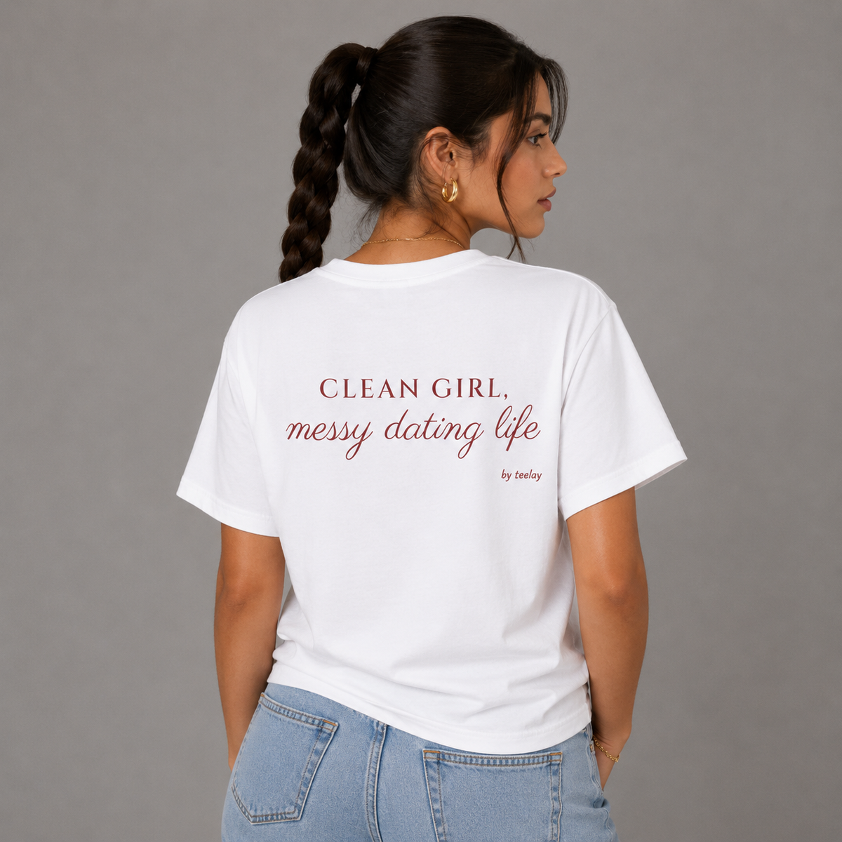 Woman from behind wearing a white t shirt with Clean Girl Messy Dating Life printed on the back