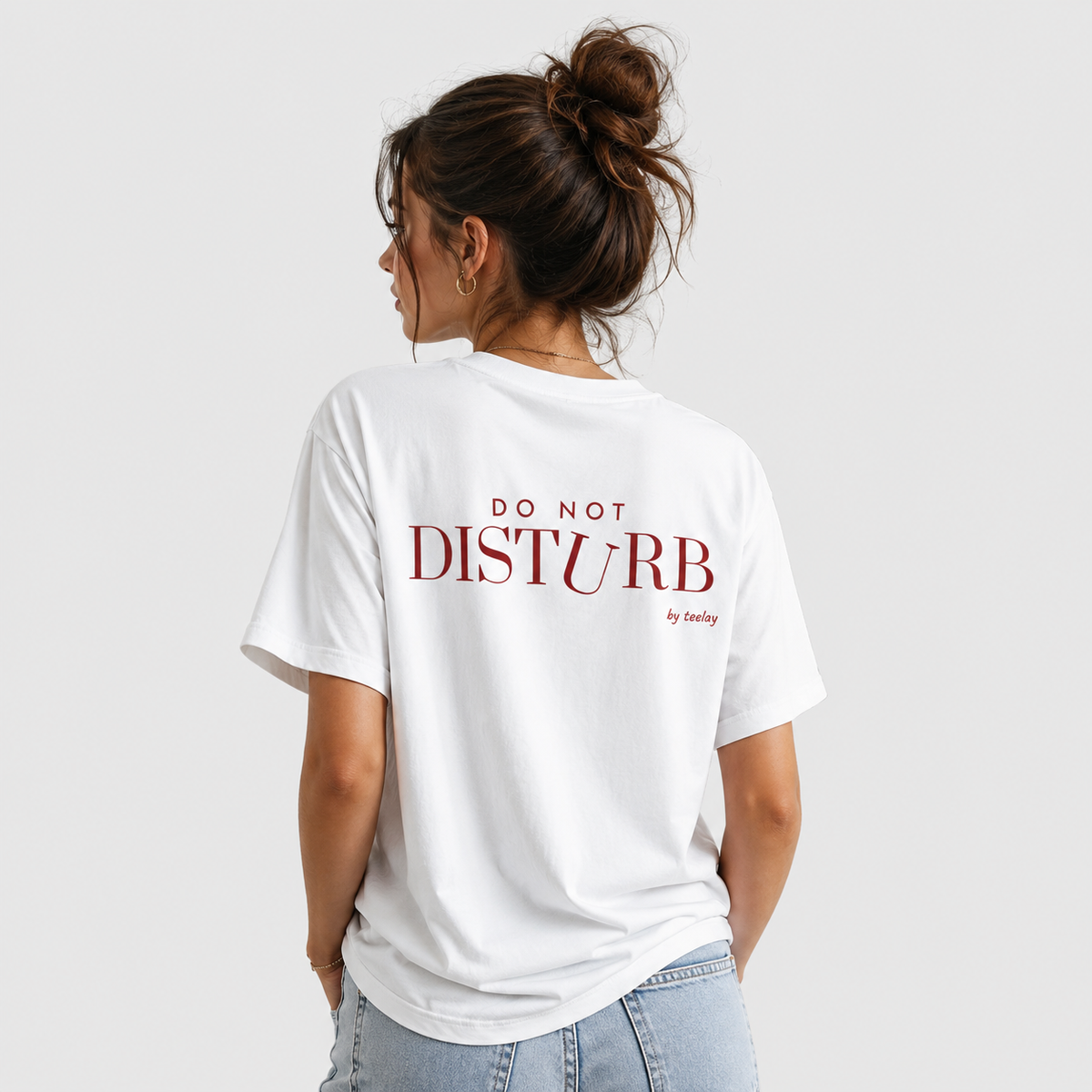Woman from behind wearing a white t shirt with Do Not Disturb printed on the back