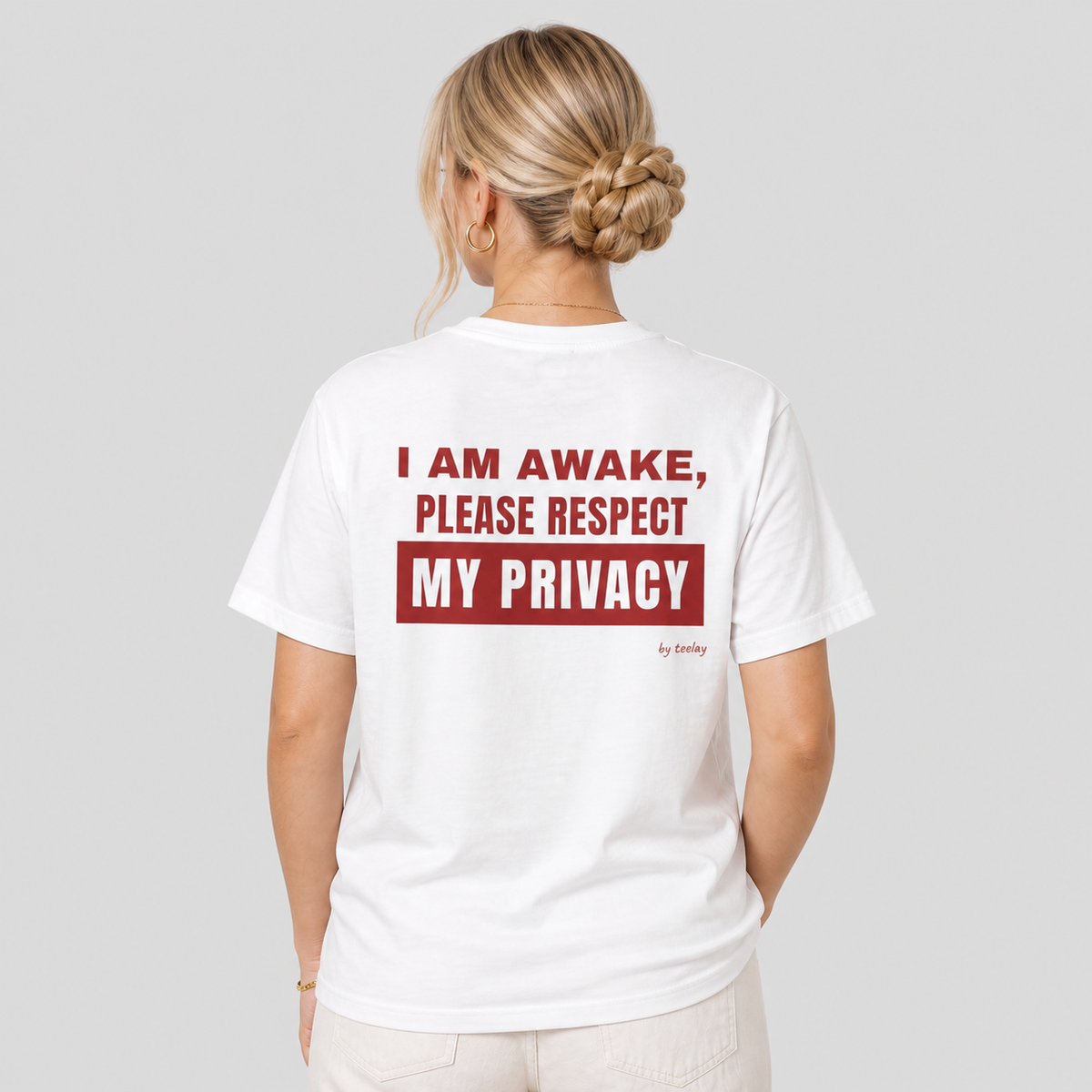 Woman from behind wearing a white t shirt with I Am Awake Please Respect My Privacy printed on the back