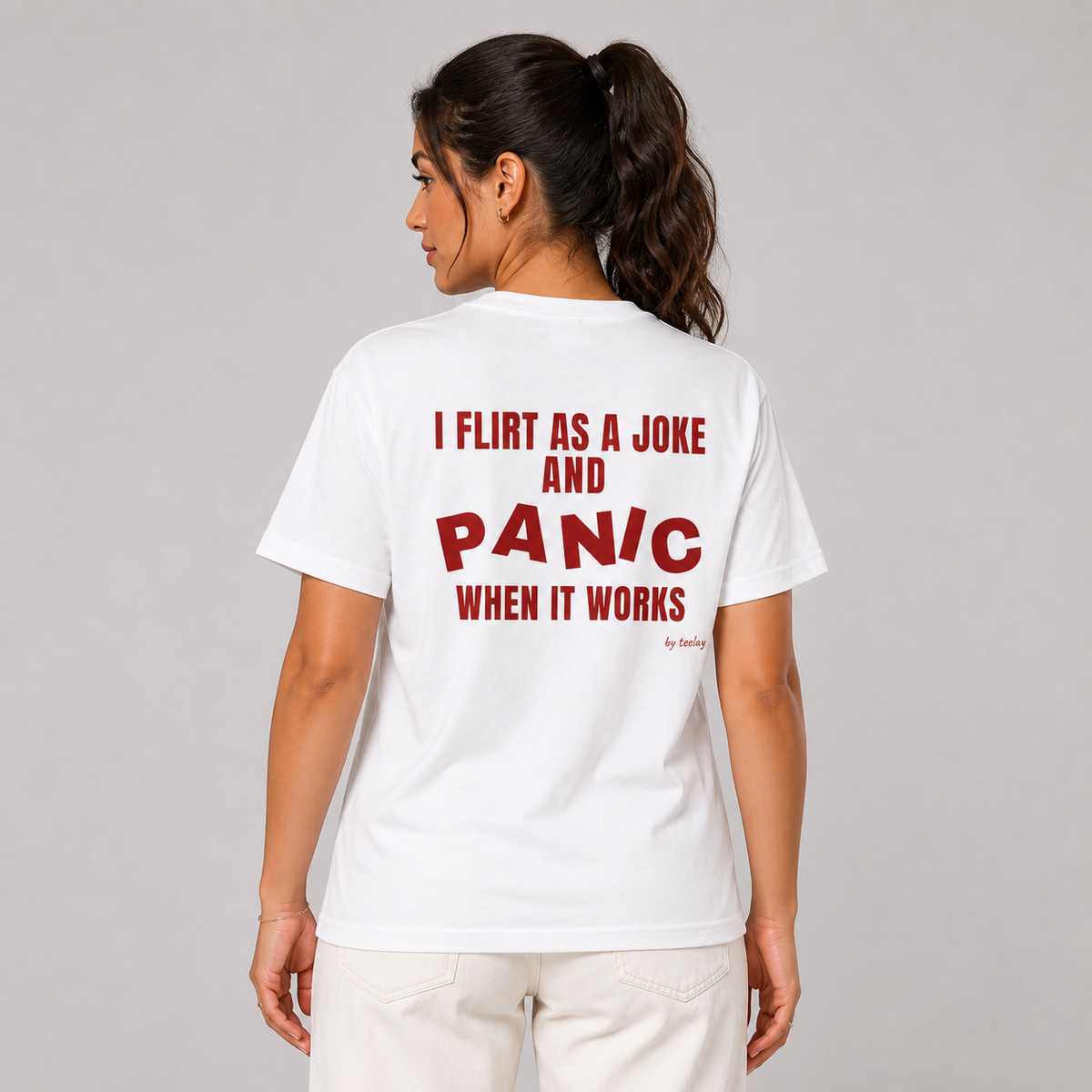 Woman from behind wearing a white t shirt with I Flirt As A Joke And Panic When It Works printed on the back