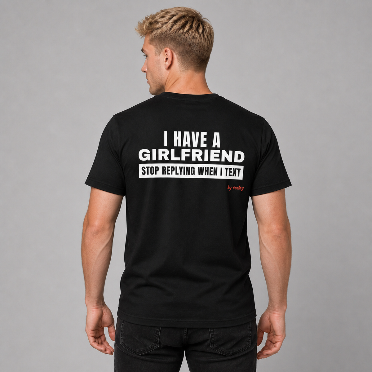Man wearing a black funny tee with I Have A Girlfriend Stop Replying When I Text printed on the back, rear view