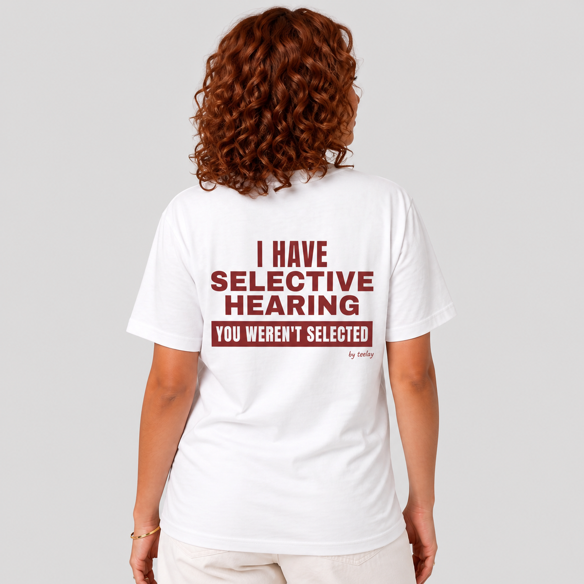 Woman from behind wearing a white t shirt with I Have Selective Hearing You Weren't Selected printed on the back