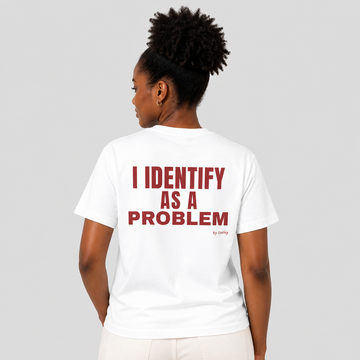 Woman from behind wearing a white t shirt with I Identify As A Problem printed on the back