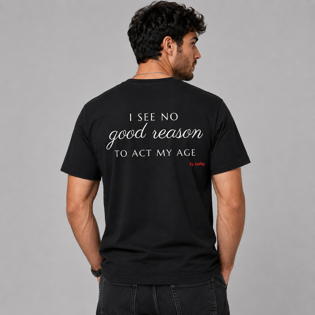 Man from behind wearing a black t shirt with I See No Good Reason To Act My Age printed on the back