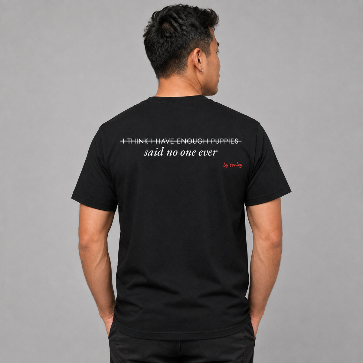 Man from behind wearing a black t shirt with I Think I Have Enough Puppies Said No One Ever printed on the back