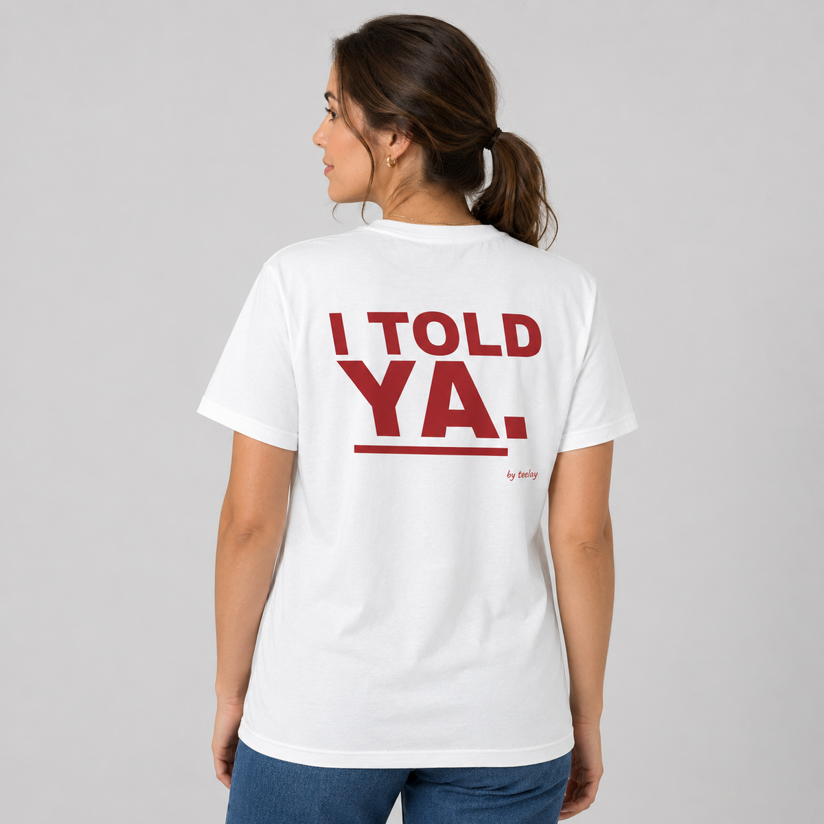 Woman from behind wearing a white t shirt with I Told Ya printed on the back