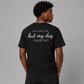 Man from behind wearing a black t shirt with I'd Love To But My Dog Said No printed on the back