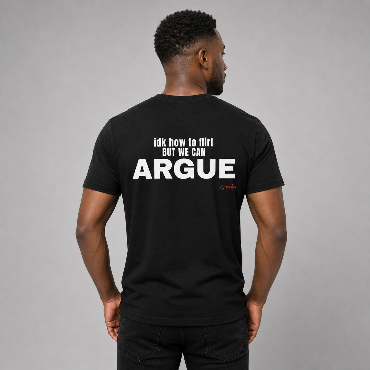 Man from behind wearing a black t shirt with IDK How To Flirt But We Can Argue printed on the back