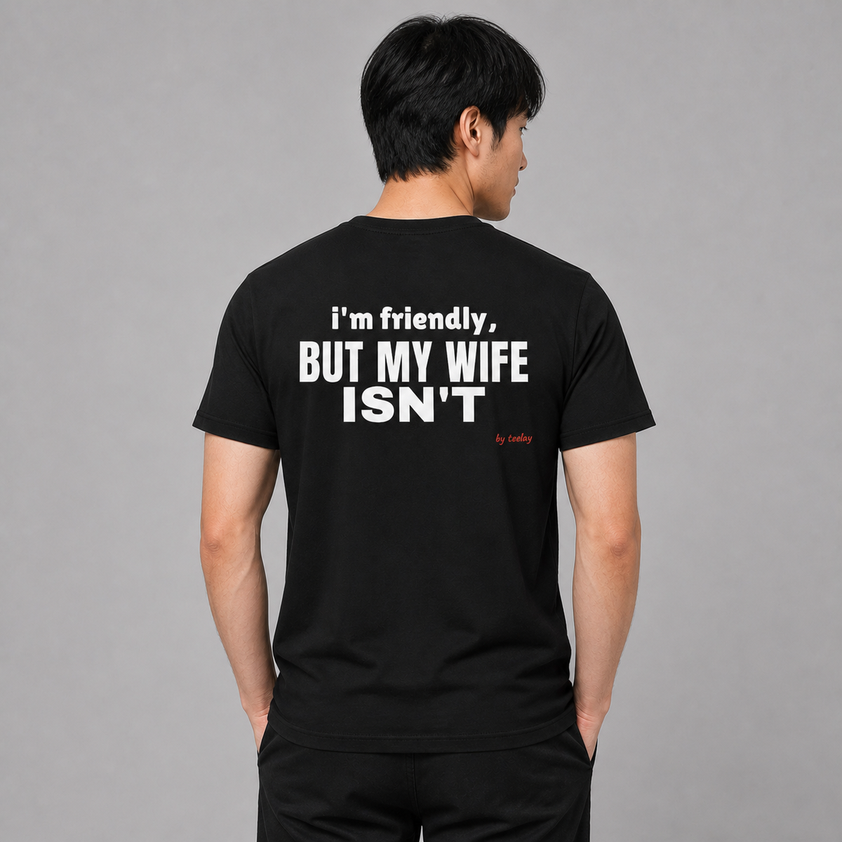 Man from behind wearing a black t shirt with I'm Friendly But My Wife Isn't printed on the back