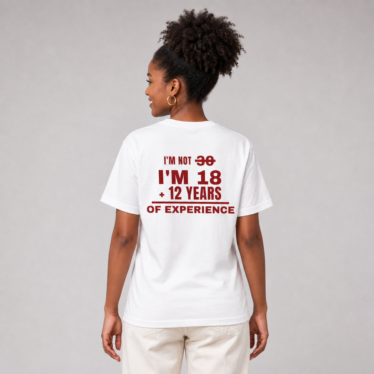 Woman from behind wearing a white t shirt with I'm Not 30 I'm 18 Plus 12 Years Of Experience printed on the back