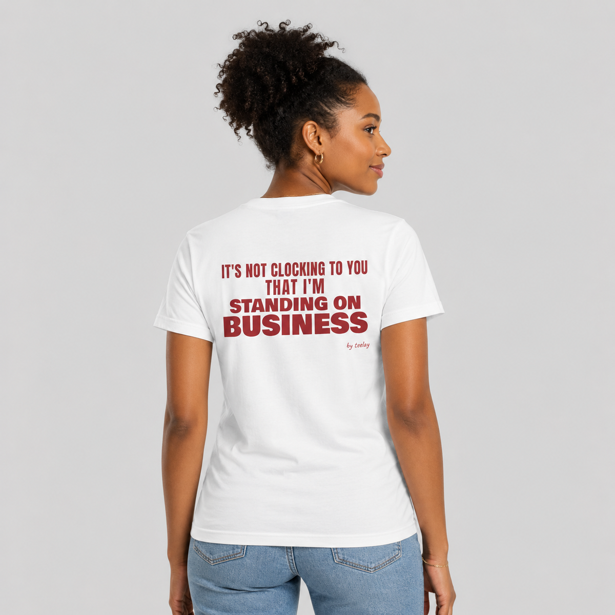 Woman from behind wearing a white t shirt with It's Not Clocking To You That I'm Standing On Business printed on the back