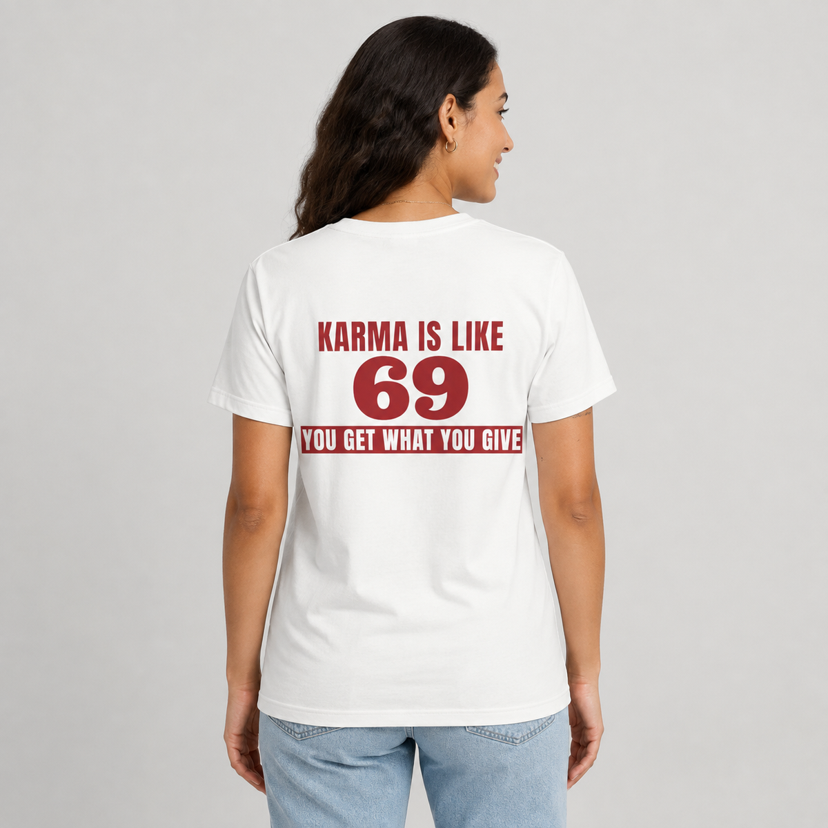 Woman from behind wearing a white t shirt with Karma Is Like 69 You Get What You Give printed on the back