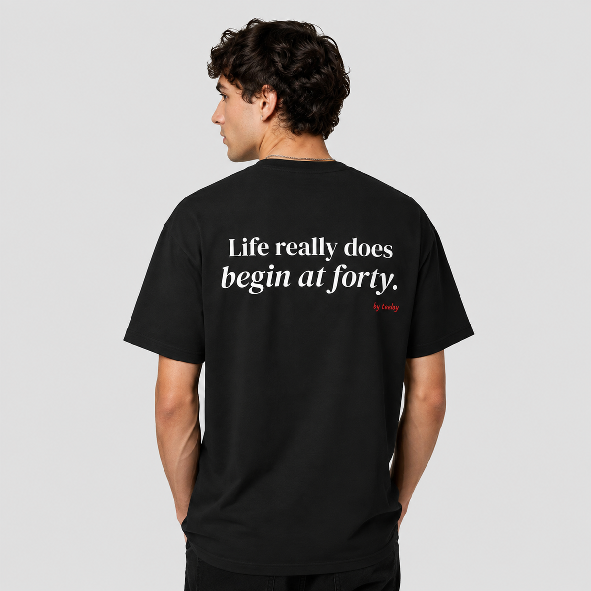 Man from behind wearing a black t shirt with Life Really Does Begin At Forty printed on the back