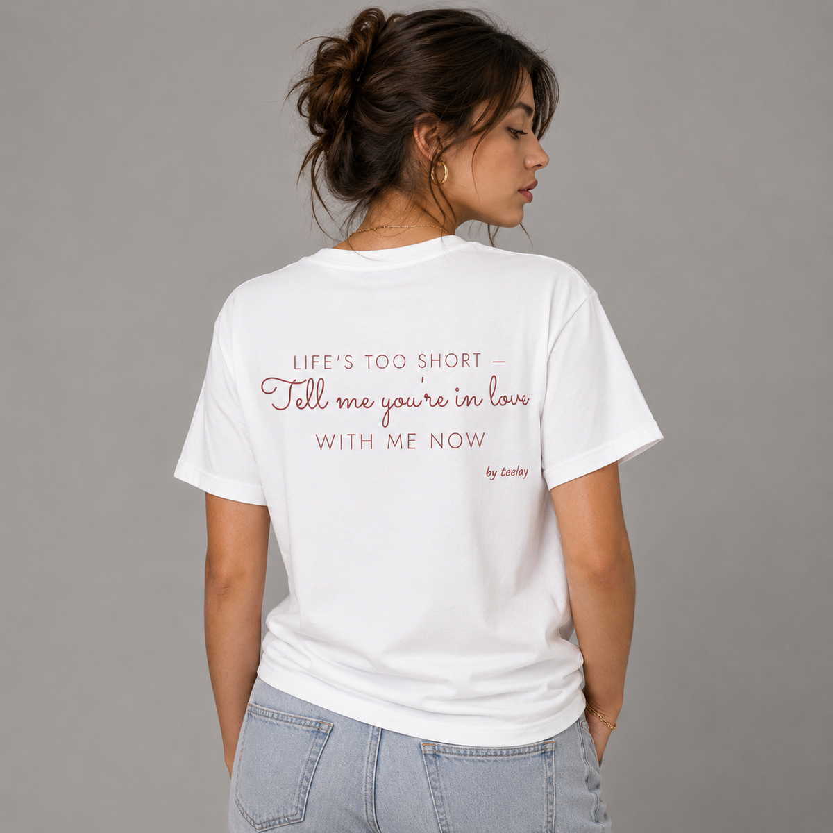 Woman from behind wearing a white t shirt with Life's Too Short Tell Me You're In Love With Me Now printed on the back