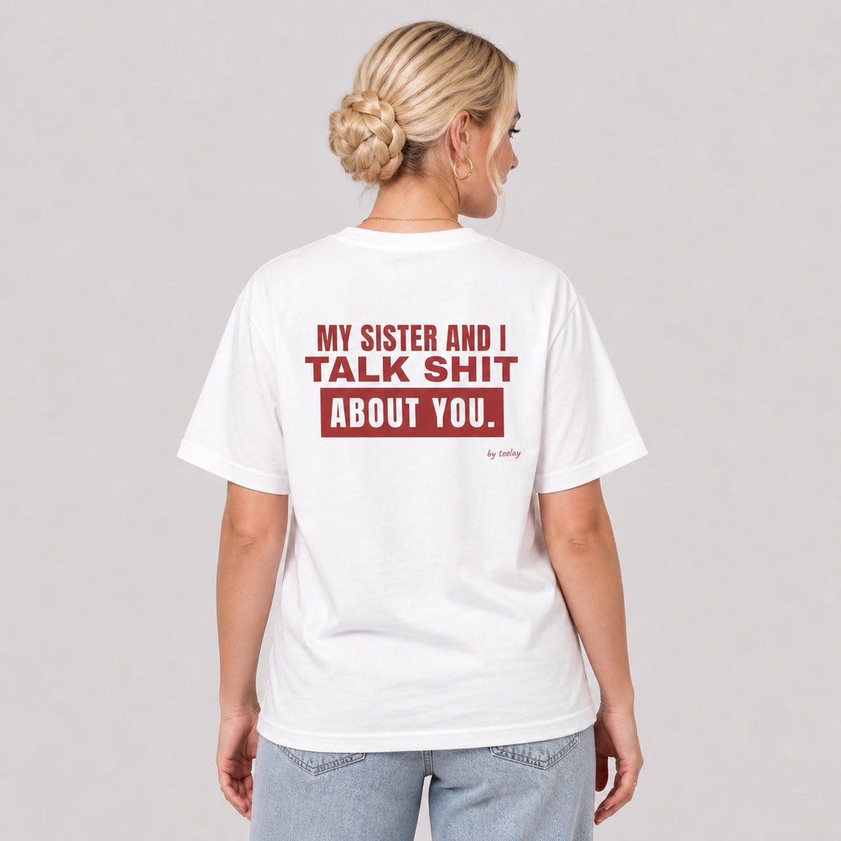 Woman from behind wearing a white t shirt with My Sister And I Talk About You printed on the back