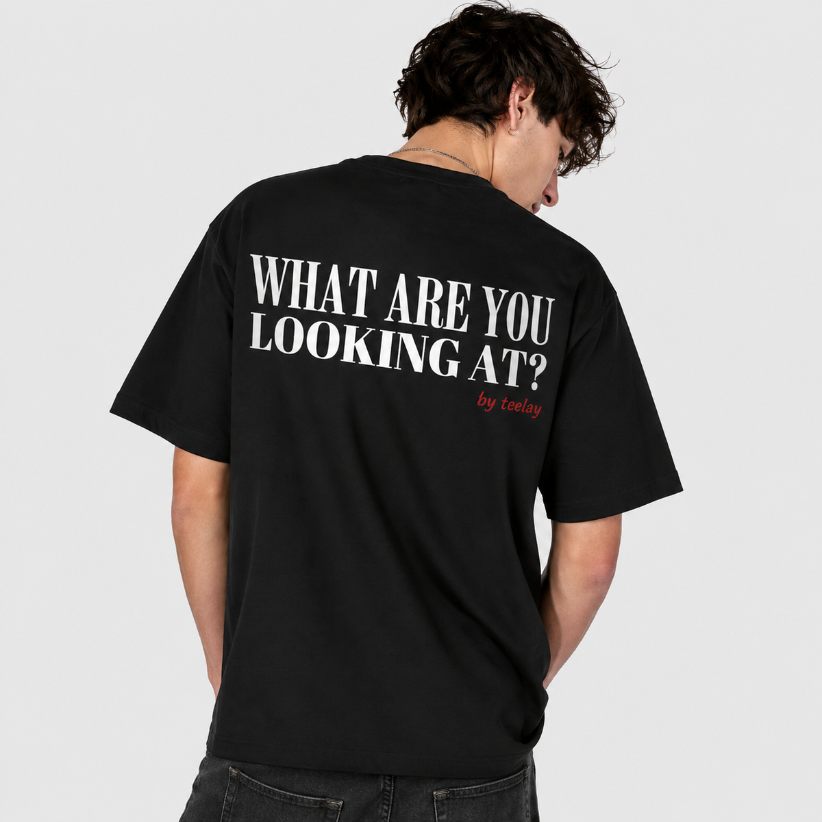 Man from behind wearing a black oversized t shirt with What Are You Looking At printed on the back