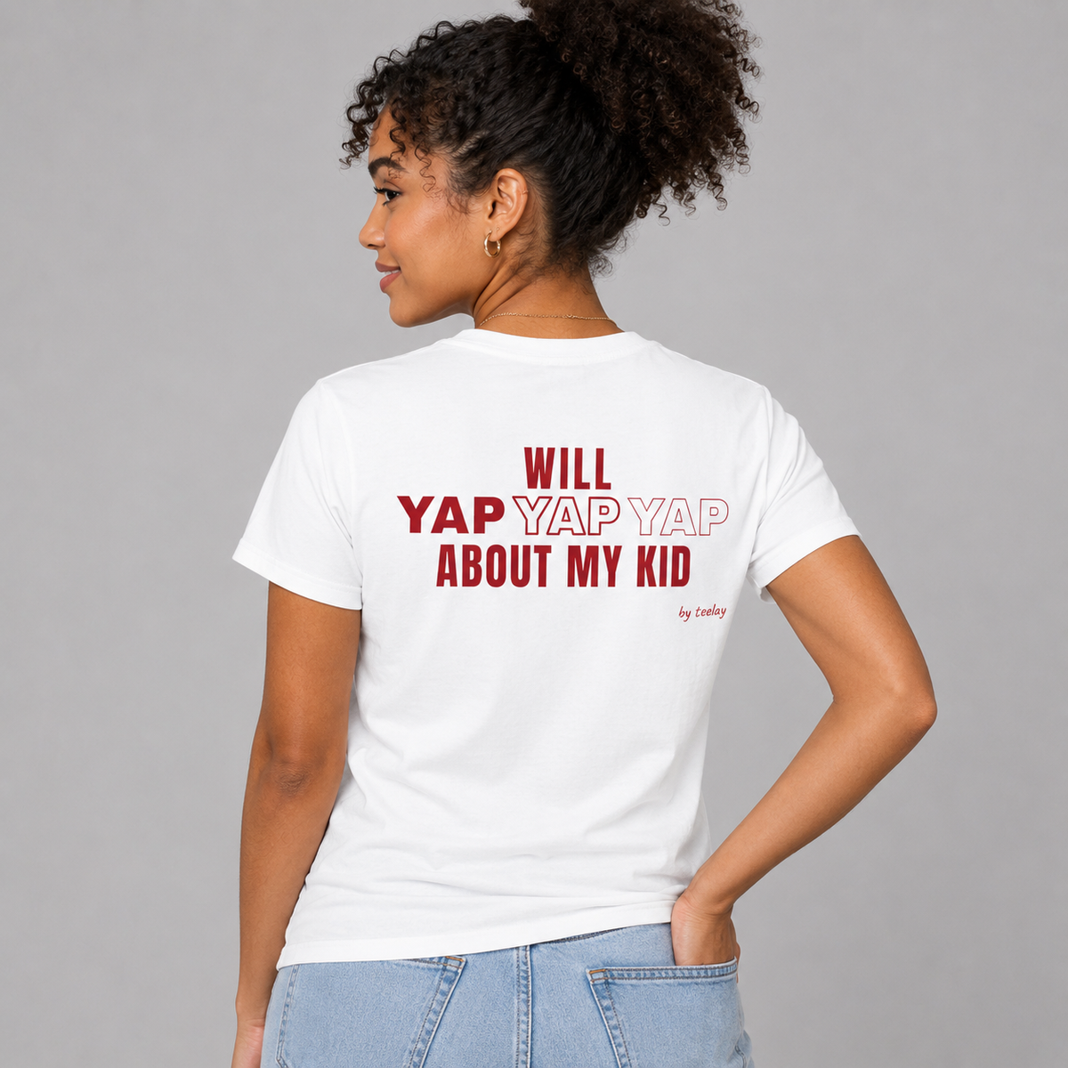 Woman from behind wearing a white t shirt with Will Yap Yap Yap About My Kid printed on the back
